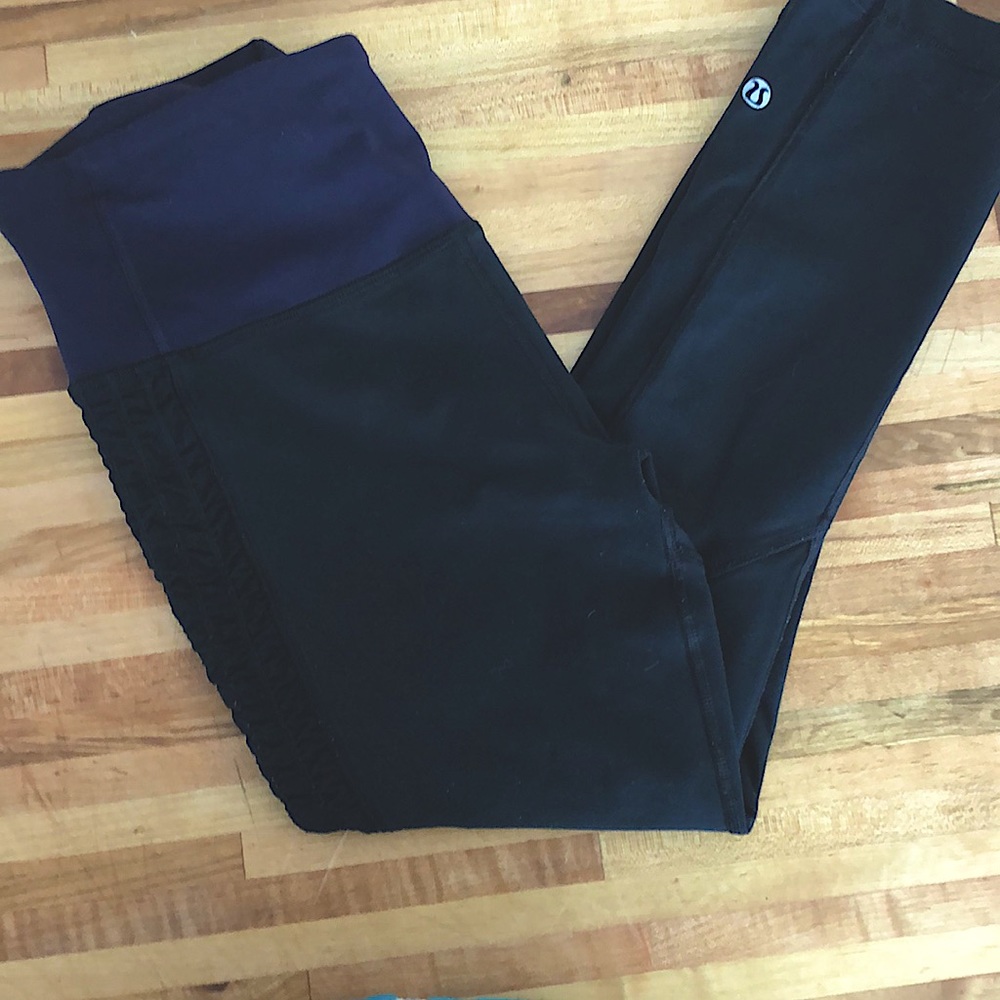 Lululemon black leggings with dark purple band and ruched on upper part of leg.